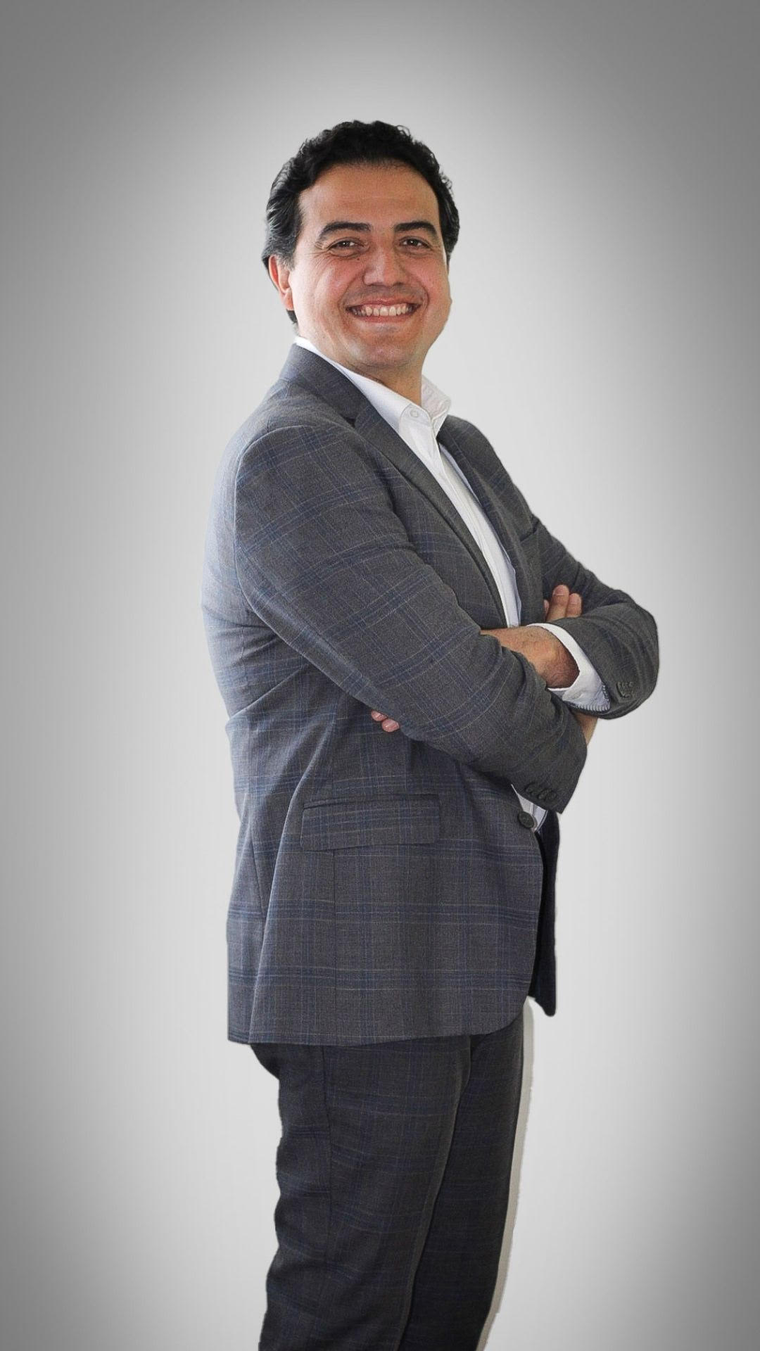 Eros Barajas con saco gris y brazos cruzados